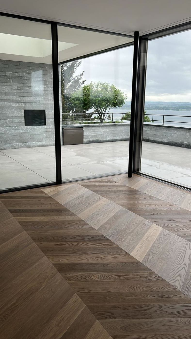Fischgrät-Parkett in Eiche in einem hellen Wohnraum mit Seeblick
