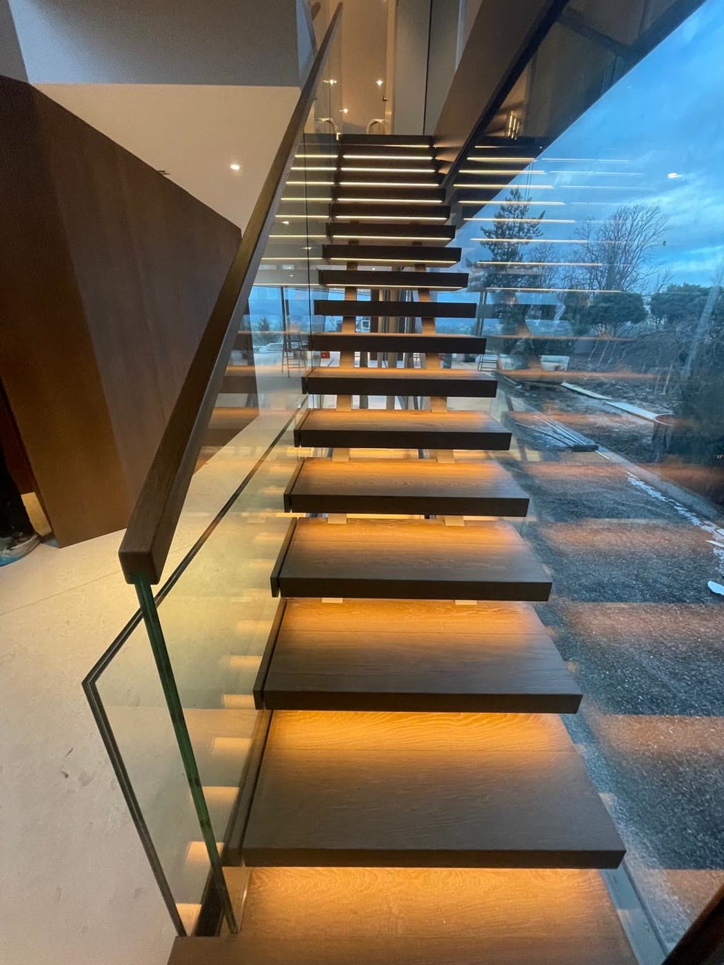 Schwebende Holztreppe mit Glasgeländer und LED-Beleuchtung
